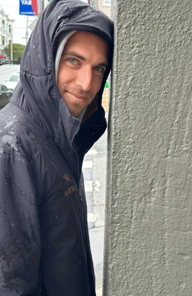 Headshot-wall-picture-scaled Cory leaning his head against a building, staring at the camera